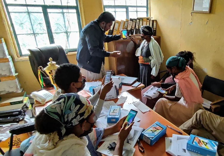 Ethiopian women beekeepers seated at desks during a smartphone training session, learning to use the app